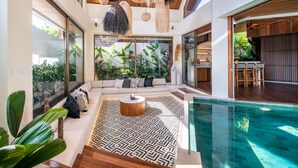 A modern interior with a pool, a seating area with a patterned rug, and a dining area with wooden furniture. - Architect's 3BR Villa, Canggu (Canggu)