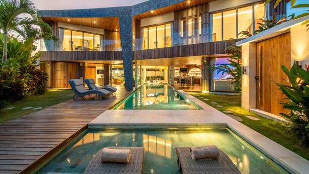 A modern two-story house with a swimming pool, lounge chairs, and a wooden deck. - Architect's 3BR Villa, Canggu (Canggu)