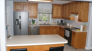 A kitchen with wooden cabinets, a stainless steel refrigerator, a dishwasher, and a stove.