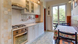Cozinha com armários brancos, fogão a gás e chão de azulejos.