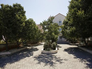 Stroll through the serene courtyard surrounded by lush trees and a charming building with a red roof.