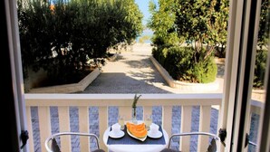 A balcony with two chairs and a table, overlooking a paved pathway flanked by greenery.