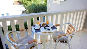 Un balcon avec une table préparée pour le petit-déjeuner, comprenant un livre, des verres et une assiette de nourriture.