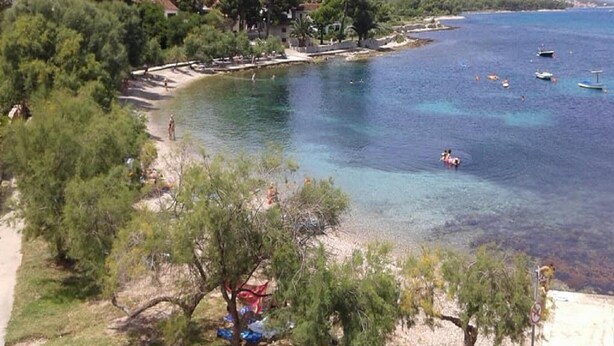 Una zona costiera con acque cristalline, una spiaggia e alcune imbarcazioni.