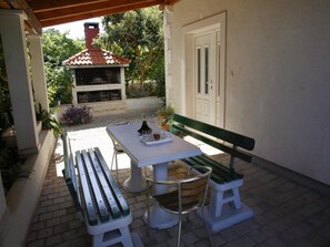 Un patio al aire libre con una mesa, dos bancos y una parrilla.