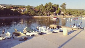 Una marina con diverse piccole imbarcazioni ormeggiate, un cielo sereno e case sullo sfondo.