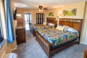 Ein Schlafzimmer mit zwei Betten, einem Deckenventilator und einer Tür, die auf einen Balkon führt.