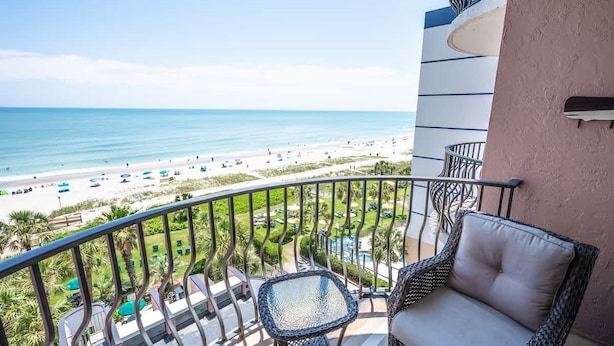 Un balcon meublé de mobilier en osier, donnant sur une plage.