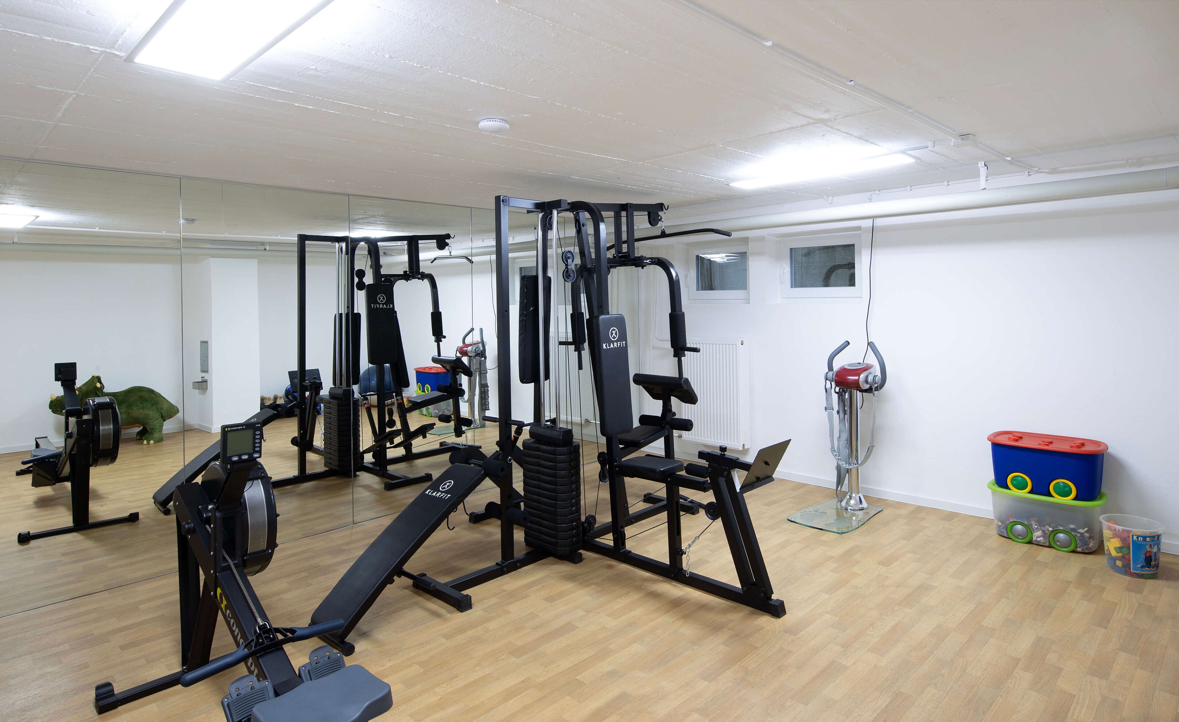 A gym with exercise equipment, a mirror, and a window.