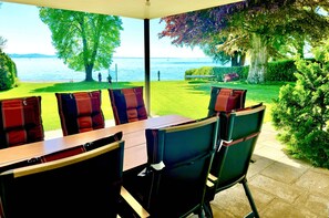 A dining area with a view of a lake, outdoor seating, and a well-maintained lawn.