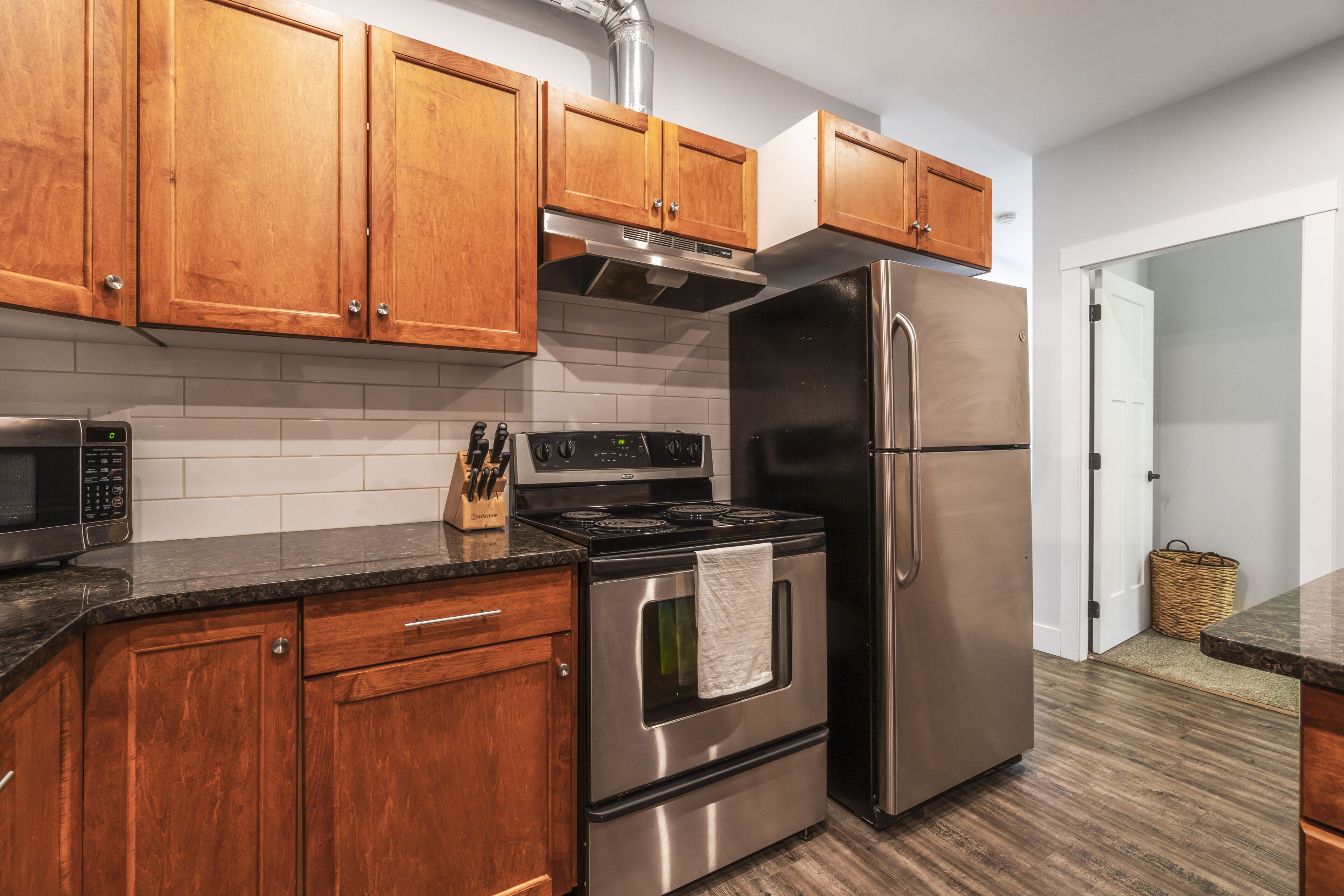 A kitchen with wooden cabinets, stainless steel appliances, and a tiled backsplash.