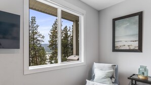A room with a large window offering a view of trees and a distant landscape. - Okanagan Lakeview Oasis, 2 Bed, 2 Bath, Sleeps 6 (Vernon)