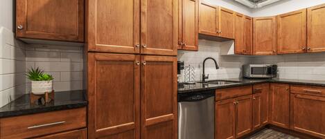 A modern kitchen with wooden cabinets, a stainless steel dishwasher, and a microwave.