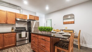 A modern kitchen with wooden cabinets, stainless steel appliances, and a central island with a plant. - Okanagan Lakeview Oasis, 2 Bed, 2 Bath, Sleeps 6 (Vernon)