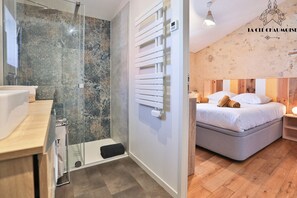 Ein modernes Badezimmer mit Duschabtrennung aus Glas, einem weißen Handtuchhalter und Holzboden.