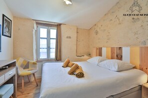 Ein Hotelzimmer mit Bett, Schreibtisch, Stuhl und Fenster.