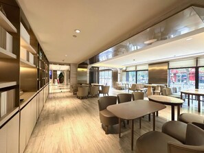 A modern interior with a long corridor leading to a seating area with tables and chairs. - Ji Hotel Shanghai Jiuting Street (Shanghai)