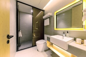 A modern bathroom with a glass shower enclosure, a white sink with a mirror, and a toilet. - Ji Hotel Shanghai Jiuting Street (Shanghai)