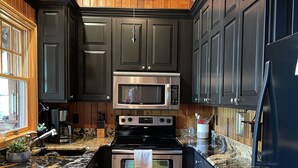 Une cuisine moderne avec des meubles de couleur sombre, des appareils électroménagers en acier inoxydable et un plafond en bois.