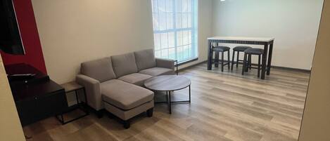 A modern living room with a sectional sofa, a round coffee table, and a dining table with chairs.