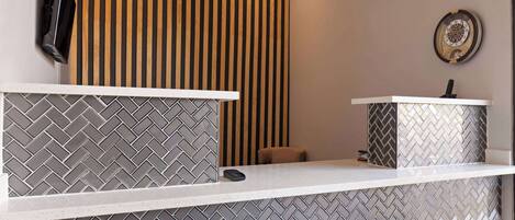 A reception area with a herringbone tile pattern, a wooden slat wall, and a small seating area.