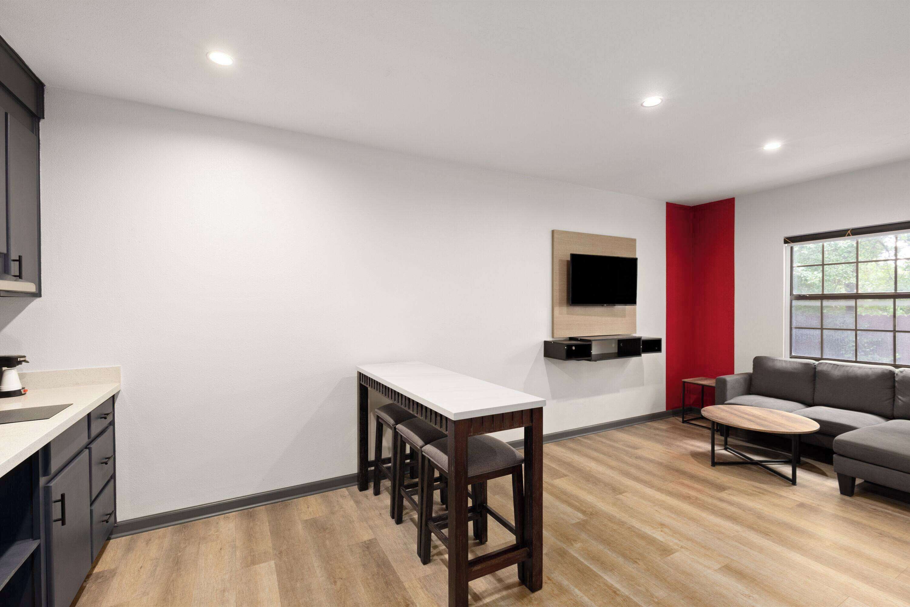 A modern living room with a sofa, a coffee table, and a dining area with a table and chairs.