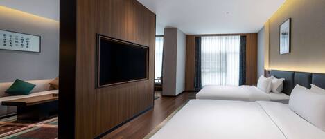 Une chambre d’hôtel moderne dotée d’une grande télévision à écran plat, de deux lits, d’un mur décoratif en bois et d’une grande fenêtre avec des rideaux.