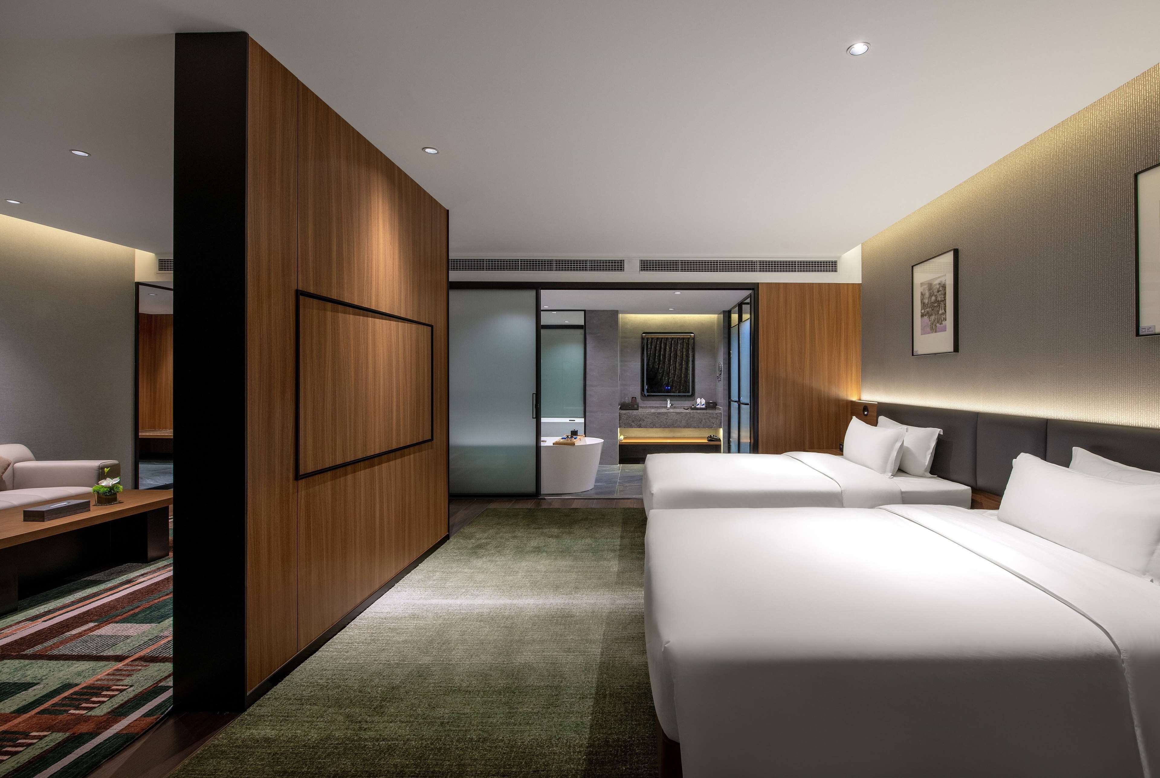 Una habitación de hotel moderna con una cama grande, un escritorio y una zona de estar.