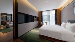 A modern hotel room with a large bed, a seating area with a table and chairs, a TV mounted on the wall, and a large window with curtains. - Tryp BY Wyndham Zizhou (Neijiang)