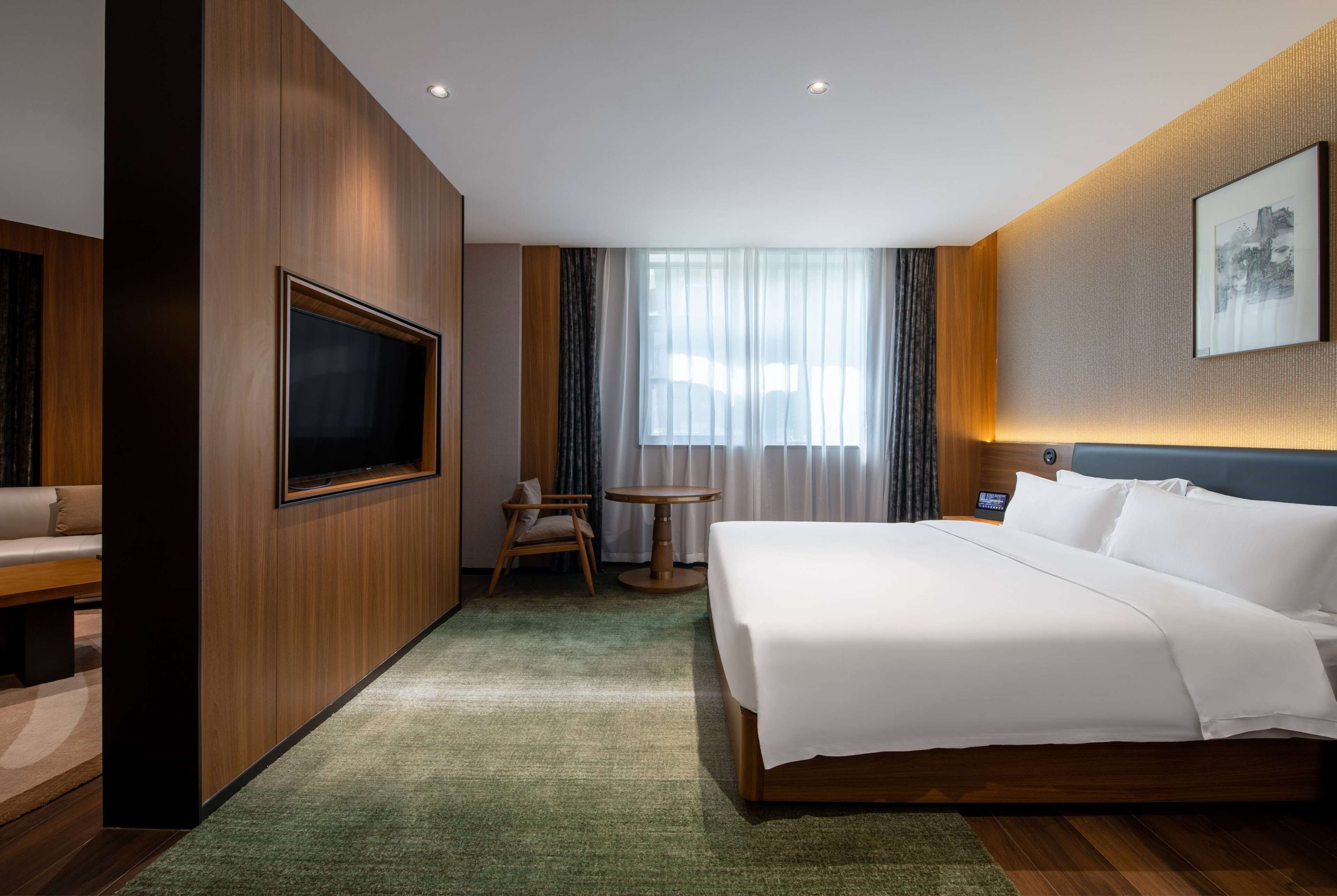 Une chambre d’hôtel avec un grand lit, un téléviseur fixé au mur, une petite table et une chaise.