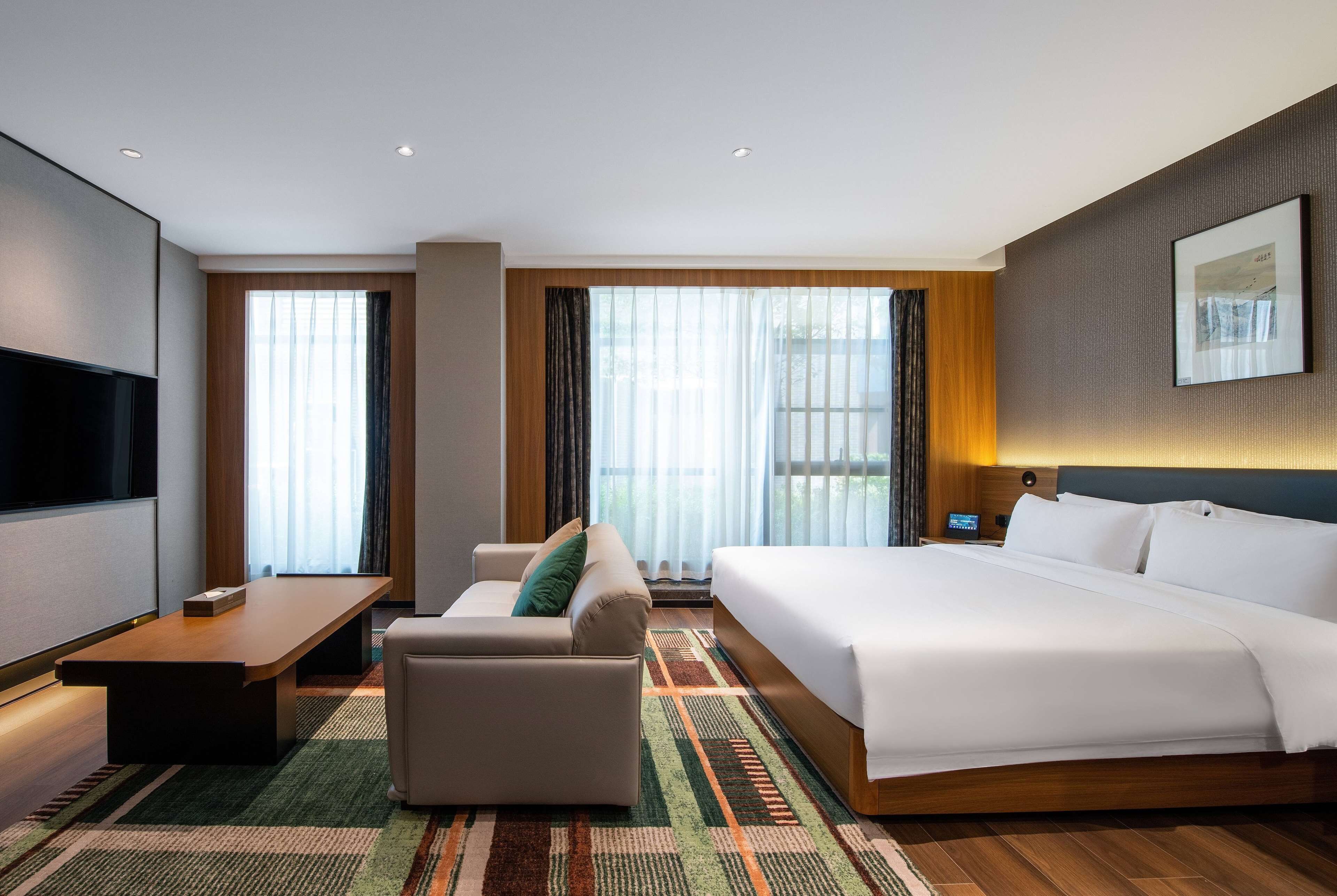 A hotel room with a bed, sofa, TV, and a desk.
