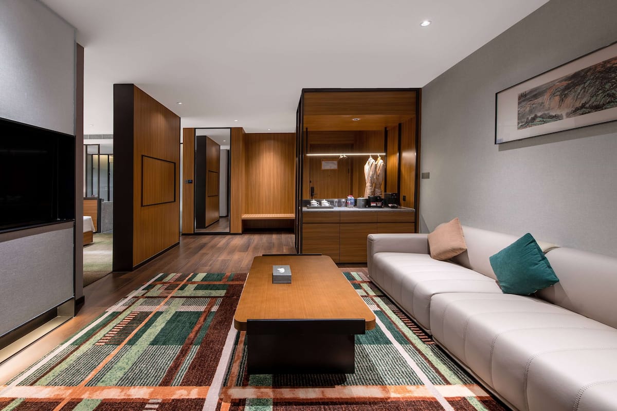 A modern hotel room with a sofa, a coffee table, a TV, and a wardrobe.