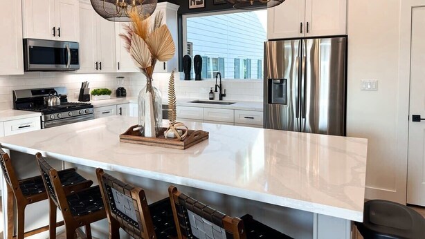 A modern kitchen with white cabinets, stainless steel appliances, and a large island with bar stools. - The Oasis Checkmate HTX Rooftop (Houston)