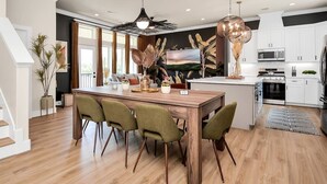 A modern kitchen with a wooden island, white cabinets, and a large painting on the wall. - The Oasis Checkmate HTX Rooftop (Houston)
