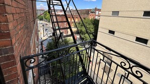 Una escalera de emergencia que da a un edificio de ladrillo, con vista a una calle y otros edificios.