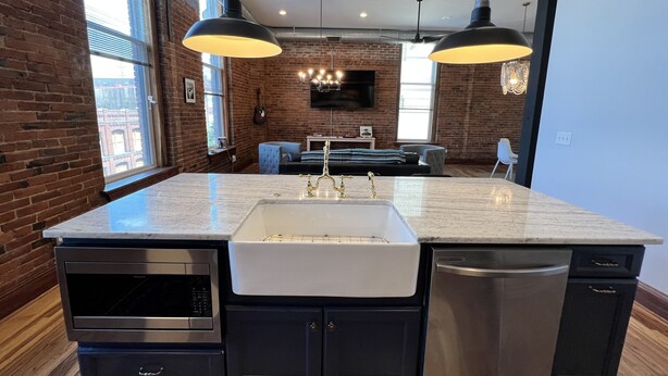 Una cocina moderna con una isla grande, electrodomésticos integrados e iluminación colgante.