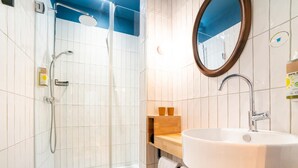 Une salle de bain moderne avec une douche à parois de verre, un lavabo blanc et un meuble-lavabo en bois.