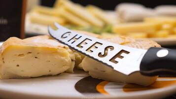 Close-up van een kaaswiel met een mesje waarop 'CHEESE' staat, op een bord, samen met stukken kaas en een schaal friet.