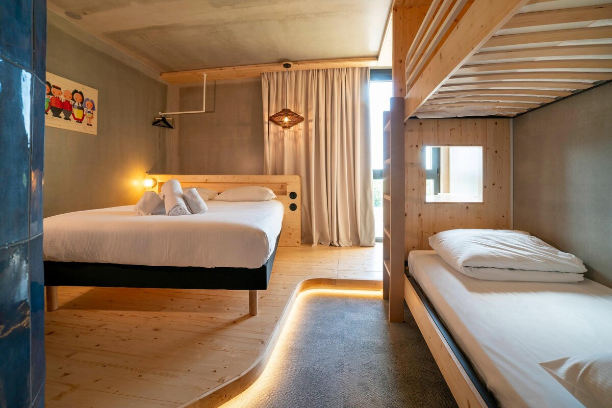 Una habitación con dos camas, techo de madera, ventana con cortinas y un cuadro en la pared.