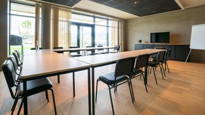 Una sala conferenze con un lungo tavolo, sedie, una lavagna e un televisore.