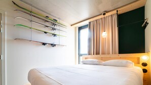 Una camera da letto con un letto, una testata, una finestra con tende e sci montati sulla parete.