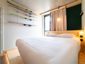 Una camera da letto con un letto, una testata, una finestra con tende e sci montati sulla parete.