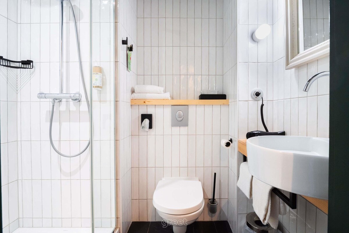 A modern bathroom with a glass shower enclosure, a toilet, a sink, and a mirror.