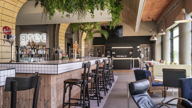 A bar area with a counter, stools, and hanging plants. - Greet Hotel Cernay Mulhouse (Cernay)