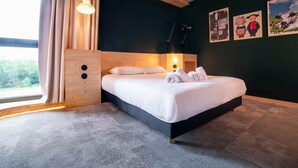 A modern hotel room with a large bed, wooden headboard, and a view of the outdoors. - Greet Hotel Cernay Mulhouse (Cernay)