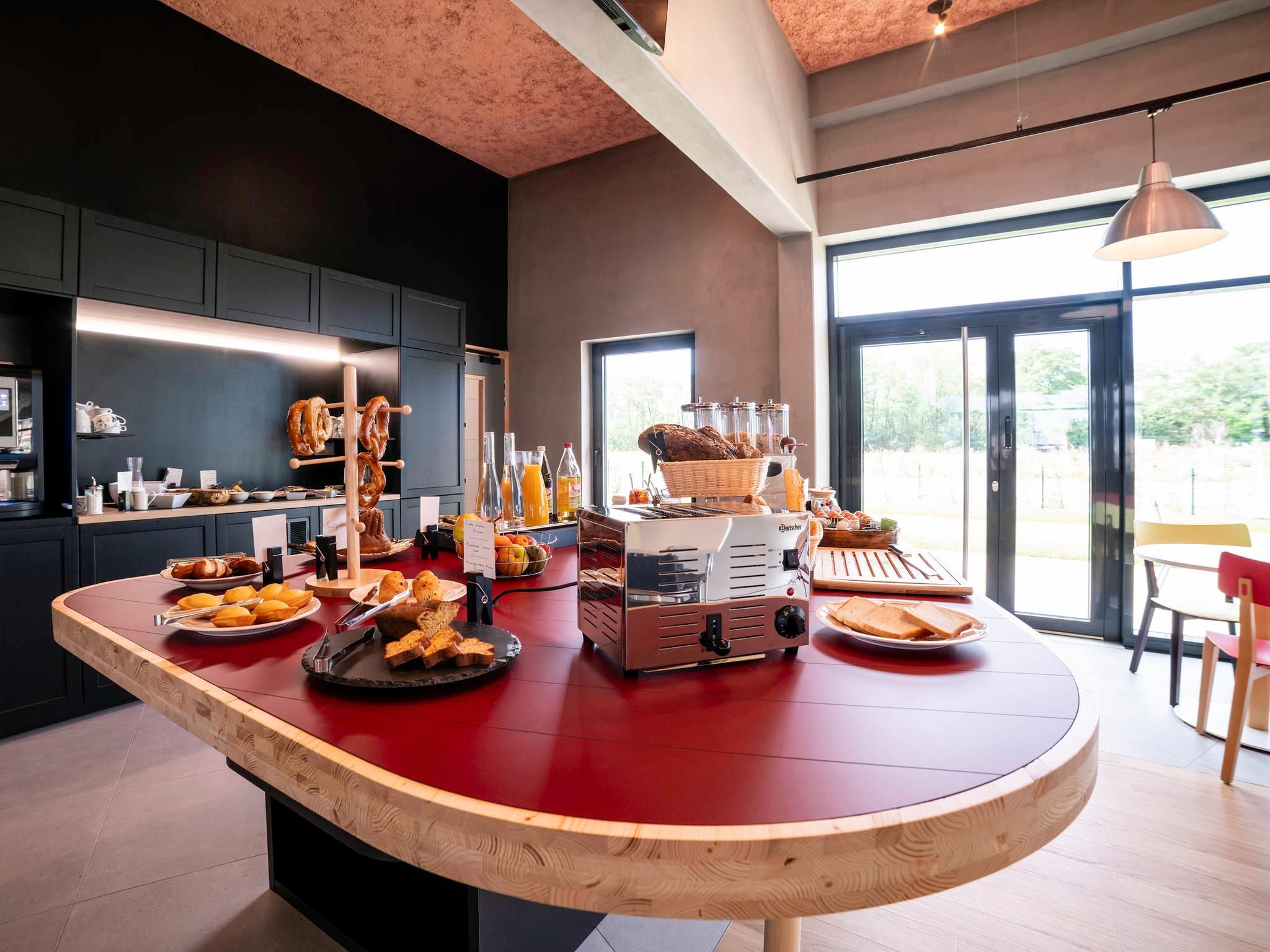 A modern kitchen with a central island, equipped with a coffee machine, bread, and various breakfast items.