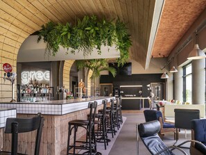Un espace bar avec un comptoir, des tabourets et des plantes suspendues.