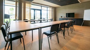 A conference room with a long table, chairs, a whiteboard, and a television. - Greet Hotel Cernay Mulhouse (Cernay)