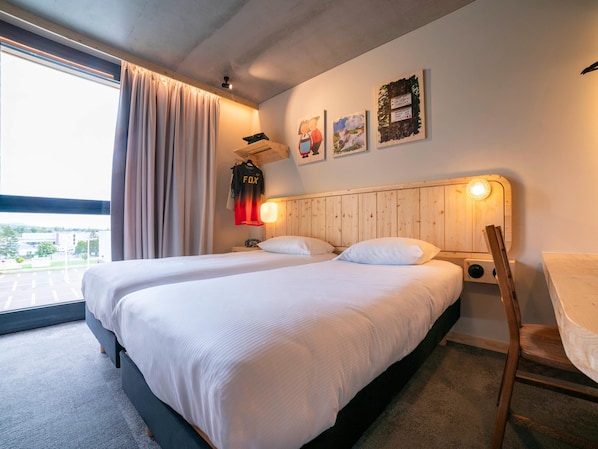 A hotel room with two beds, a wooden headboard, a window with curtains, and artwork on the wall. - Greet Hotel Cernay Mulhouse (Cernay)