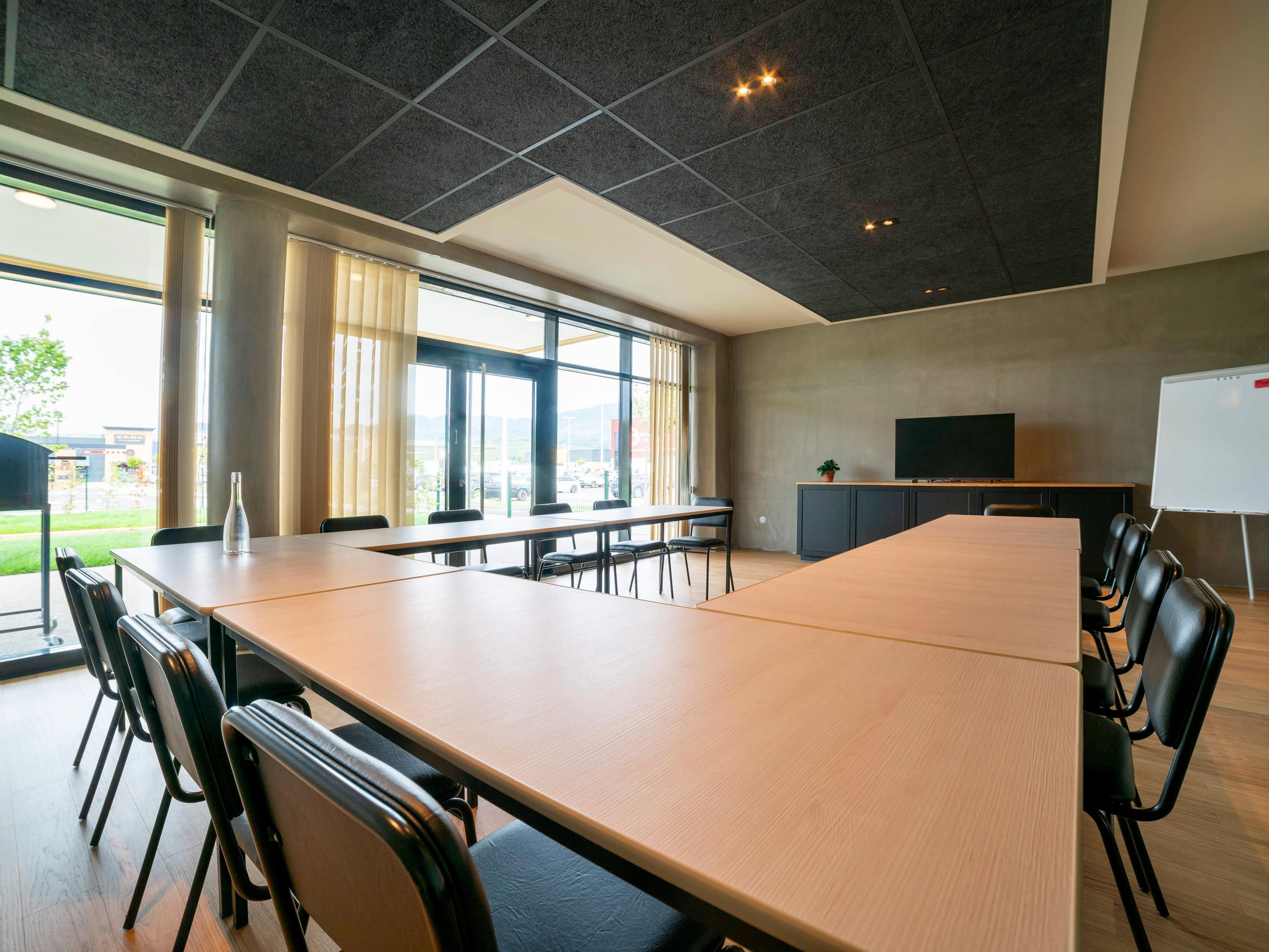 A conference room with a large table, chairs, a whiteboard, and a TV.